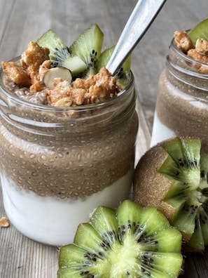a glass jar filled with food next to kiwi slices
