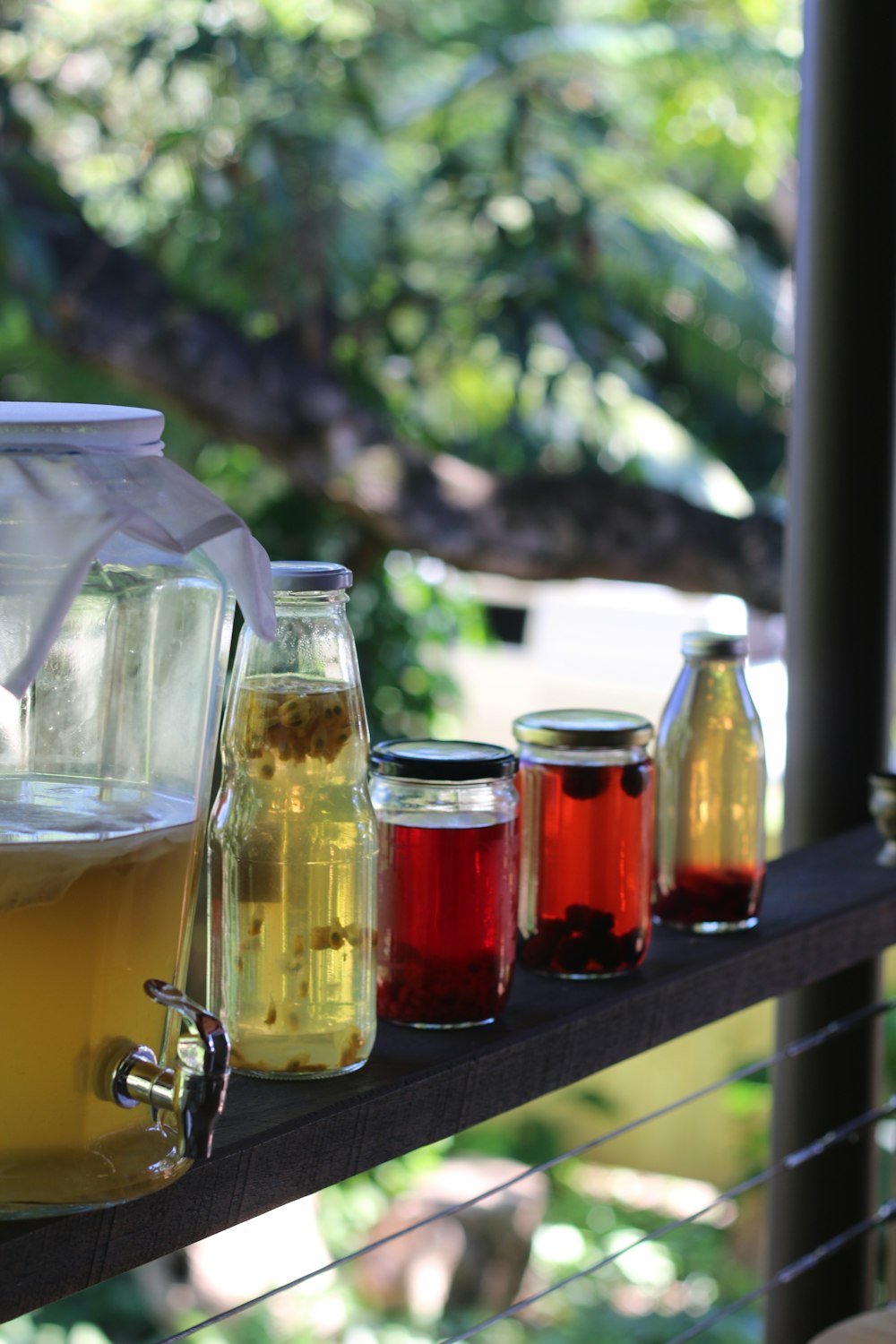 a row of jars filled with liquid sitting on top of a wooden shelf