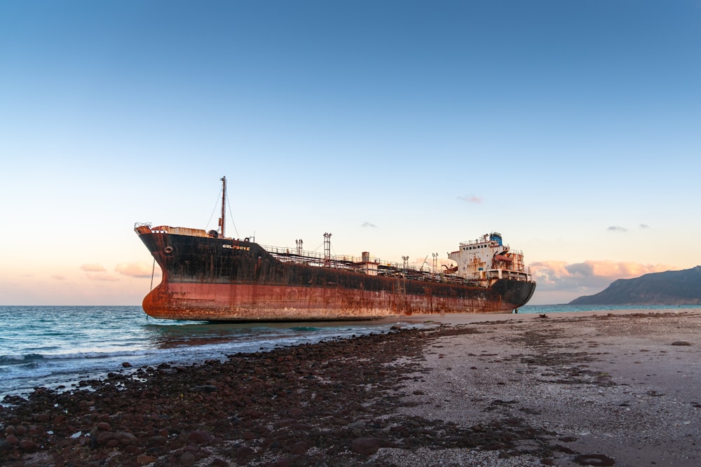 a rusted ship sitting on top of a sandy beach