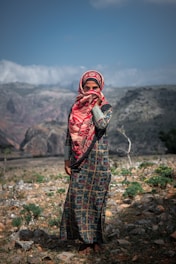 a woman in a colorful dress standing in a rocky area