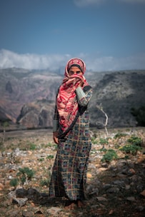 a woman in a colorful dress standing in a rocky area