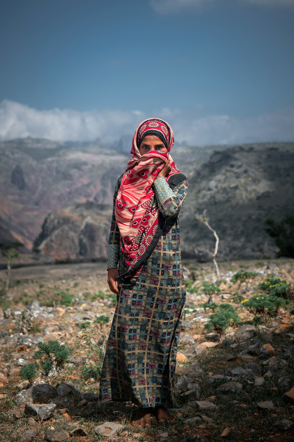 a woman in a colorful dress standing in a rocky area