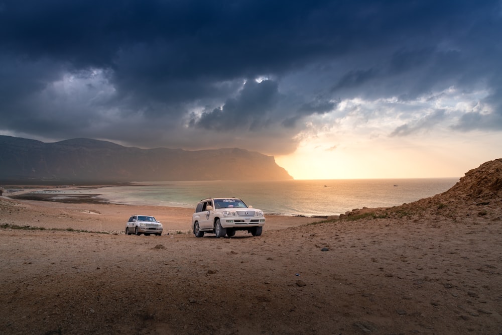 a couple of cars parked on top of a sandy beach