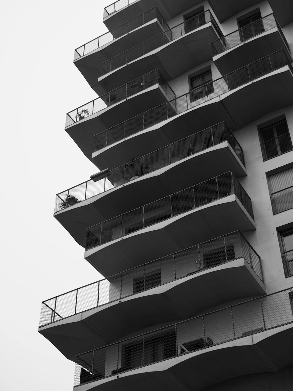 Tall modern apartment building with curved design and railings on each balcony