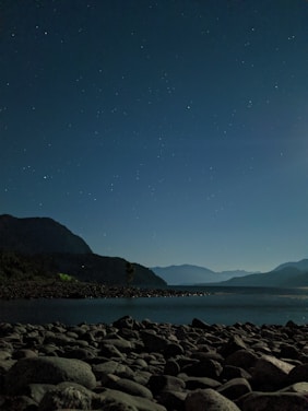 A serene landscape with a person meditating under a starry sky.