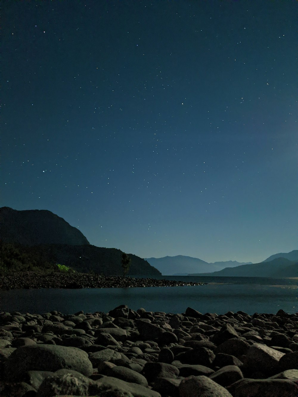 a full moon shines over a mountain lake