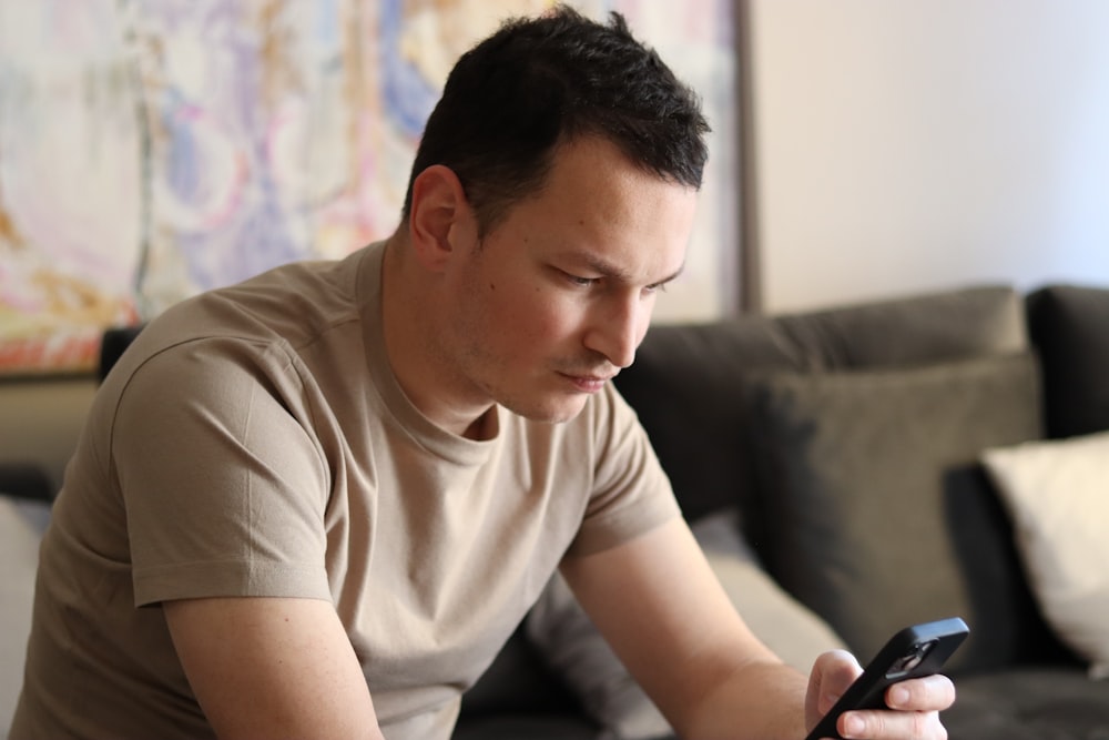 a man sitting on a couch looking at his cell phone