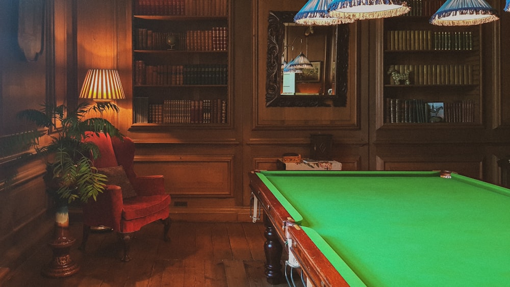 a room with a pool table, chairs and bookshelves