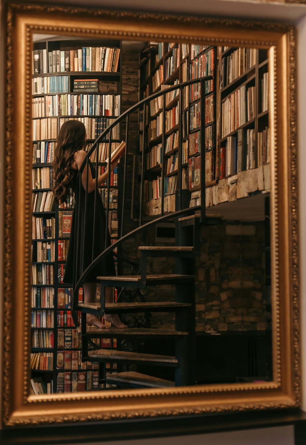 a woman standing on a stair case next to a bookshelf