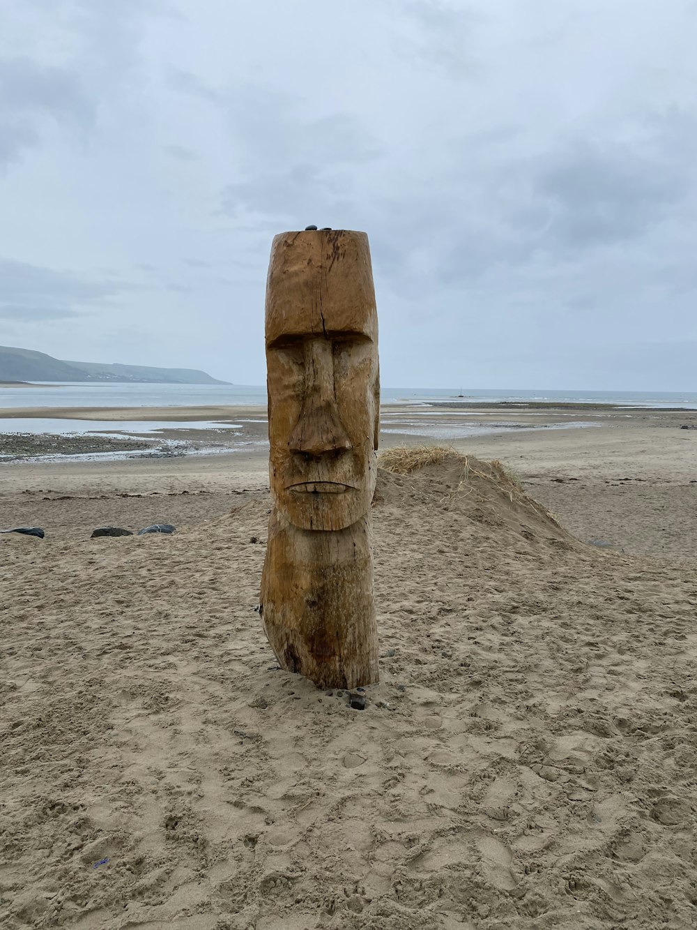 a large wooden statue sitting on top of a sandy beach