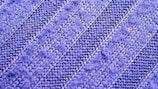 A close-up view of a textured fabric with a zigzag knit pattern. The material appears soft and has alternating light and dark blue stripes.