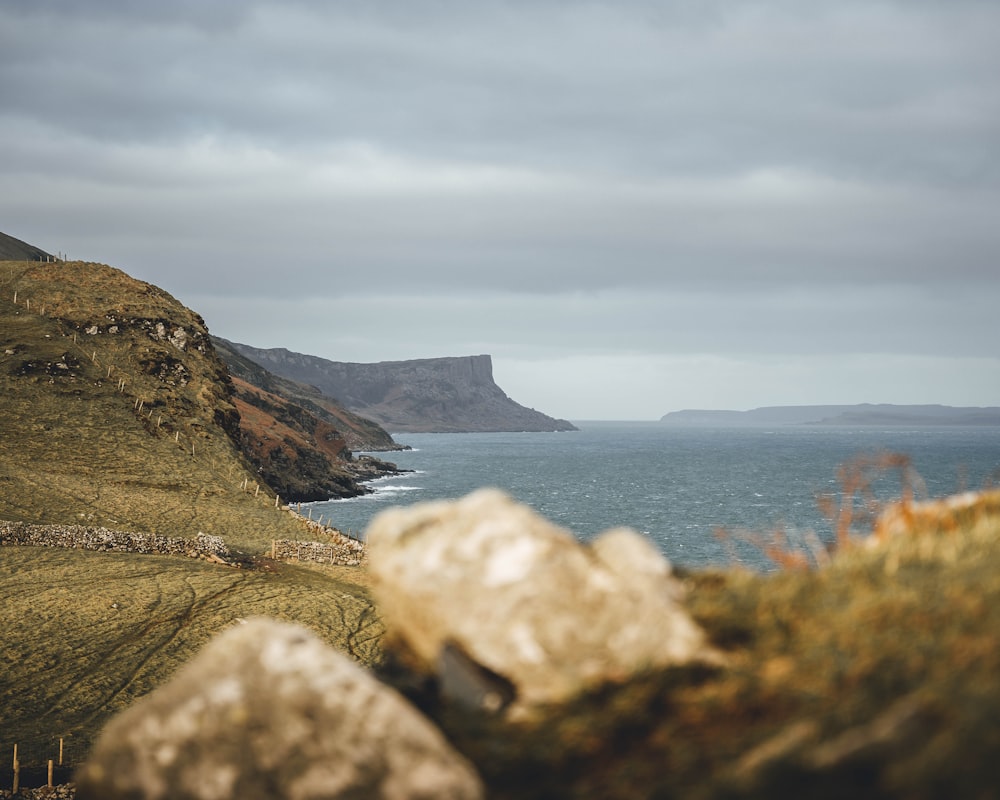 a large body of water sitting next to a lush green hillside