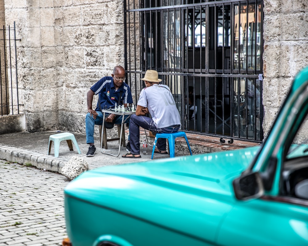 two men sitting at a table outside of a building