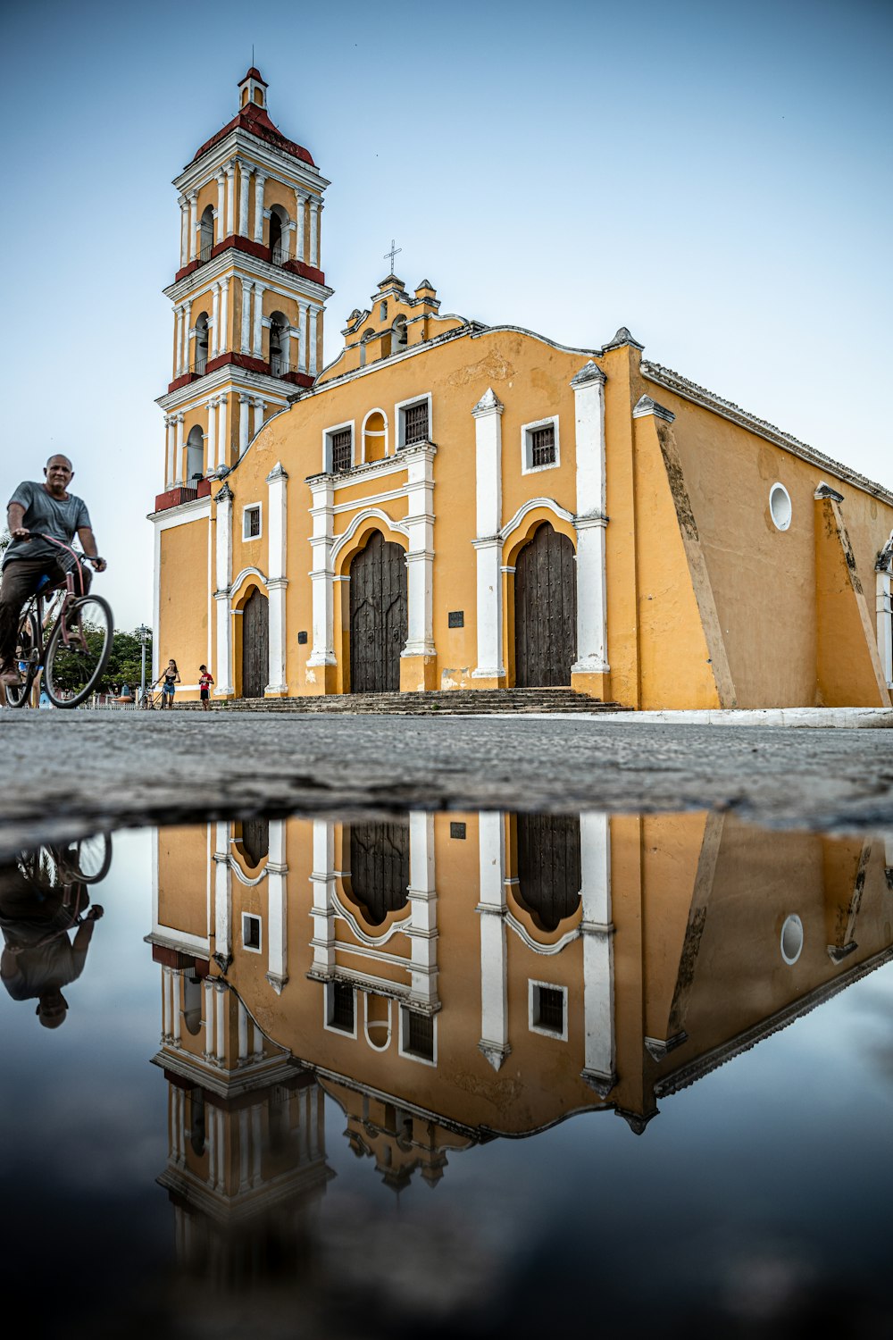 a man riding a bike past a yellow church