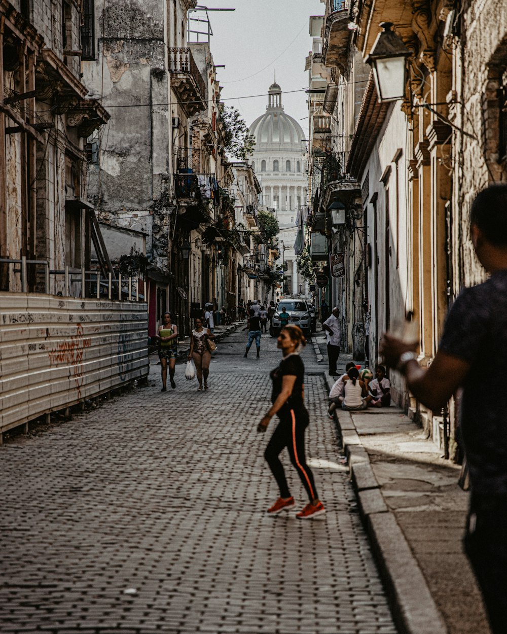 a woman walking down a street next to a tall building