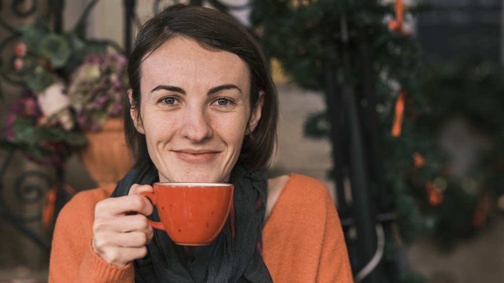 a woman holding a cup of coffee in front of her face
