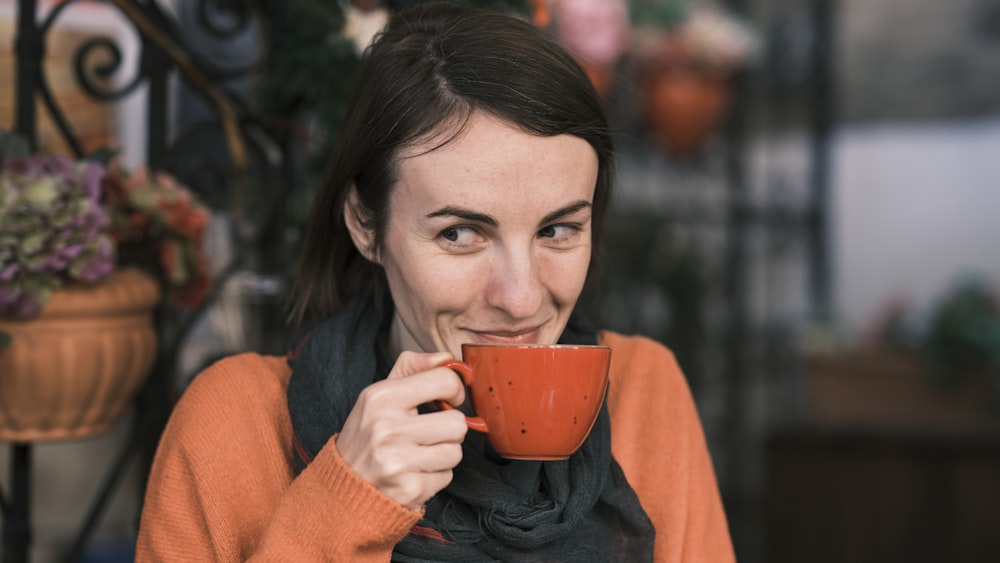 a woman holding a cup of coffee and smiling