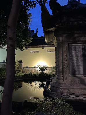 A serene resort garden featuring winding stone paths, tropical plants, and soft ambient lighting at dusk.