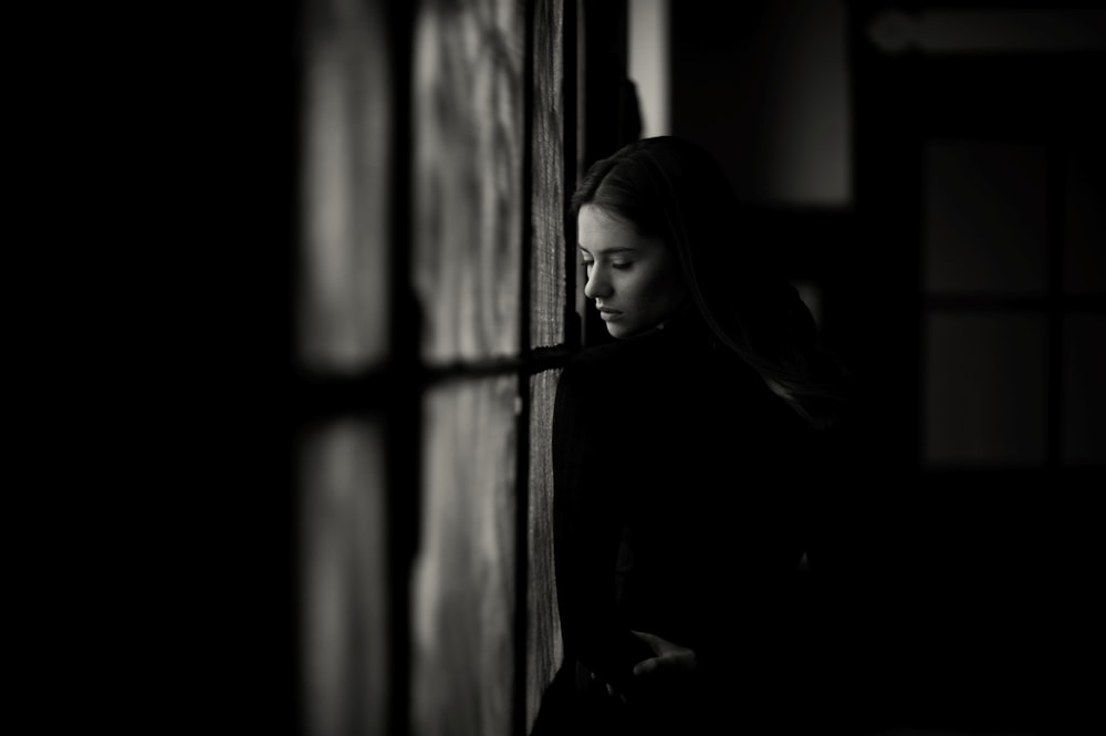 a woman leaning against a wall in a dark room