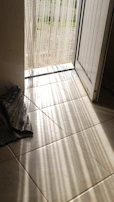A boho-style door curtain gently swaying in a sunlit doorway.
