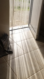 Morning light streaming through a window illuminating a prayer rug and beads.