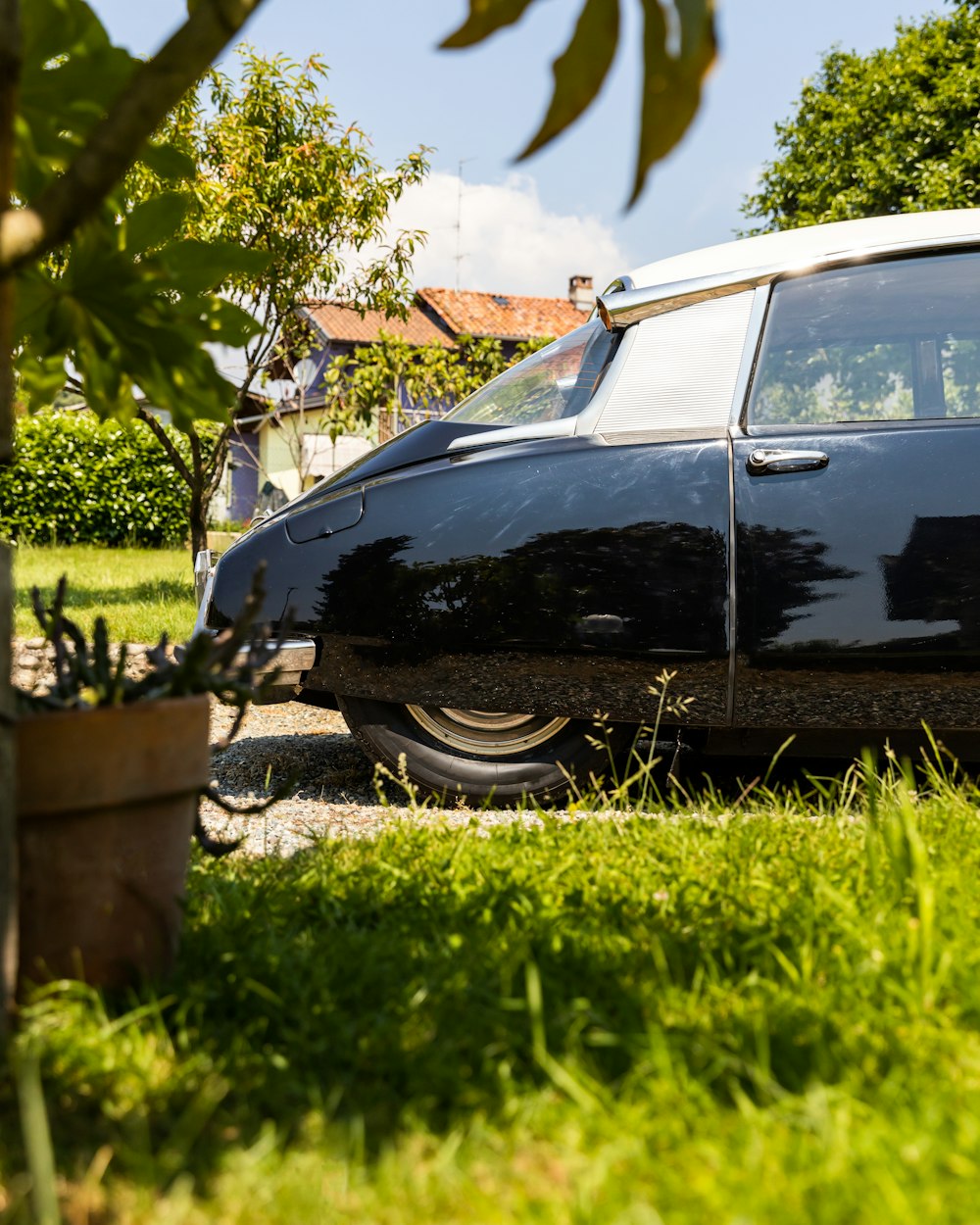 a black car parked in the grass next to a tree