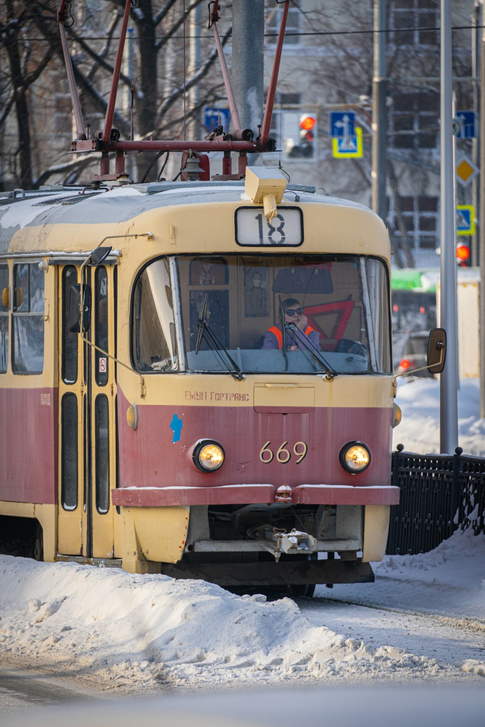 a red and yellow train traveling down a snow covered street
