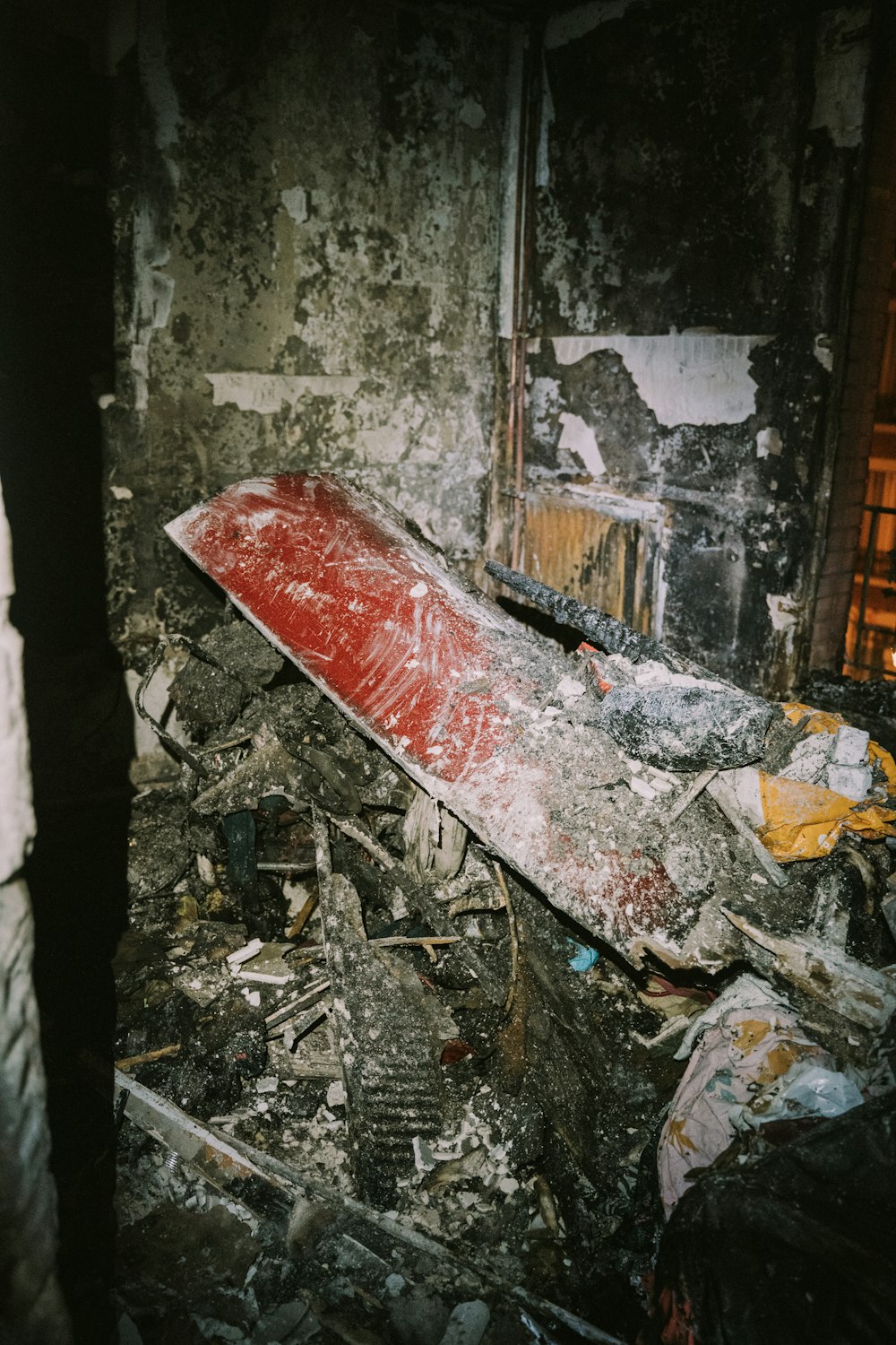 a red surfboard laying on top of a pile of rubble