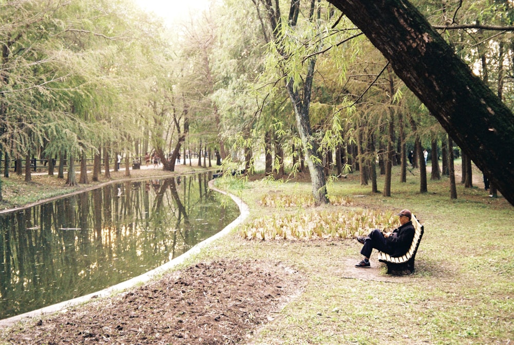 a woman sitting on a bench next to a body of water