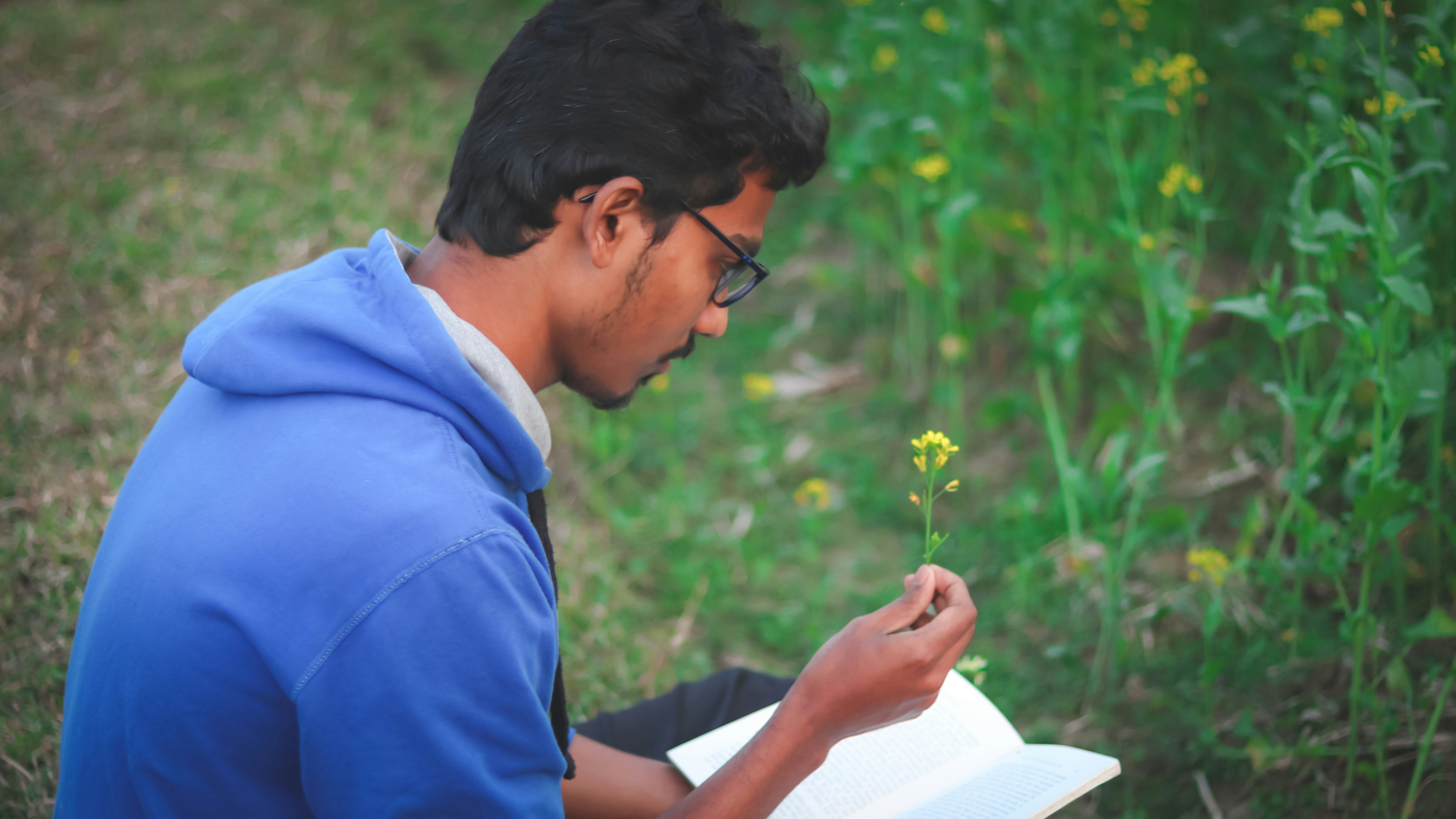 a man sitting in a field reading a book