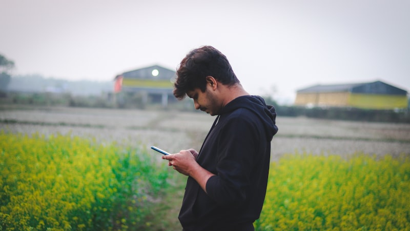 A farmer checking information on a smartphone while standing in a field