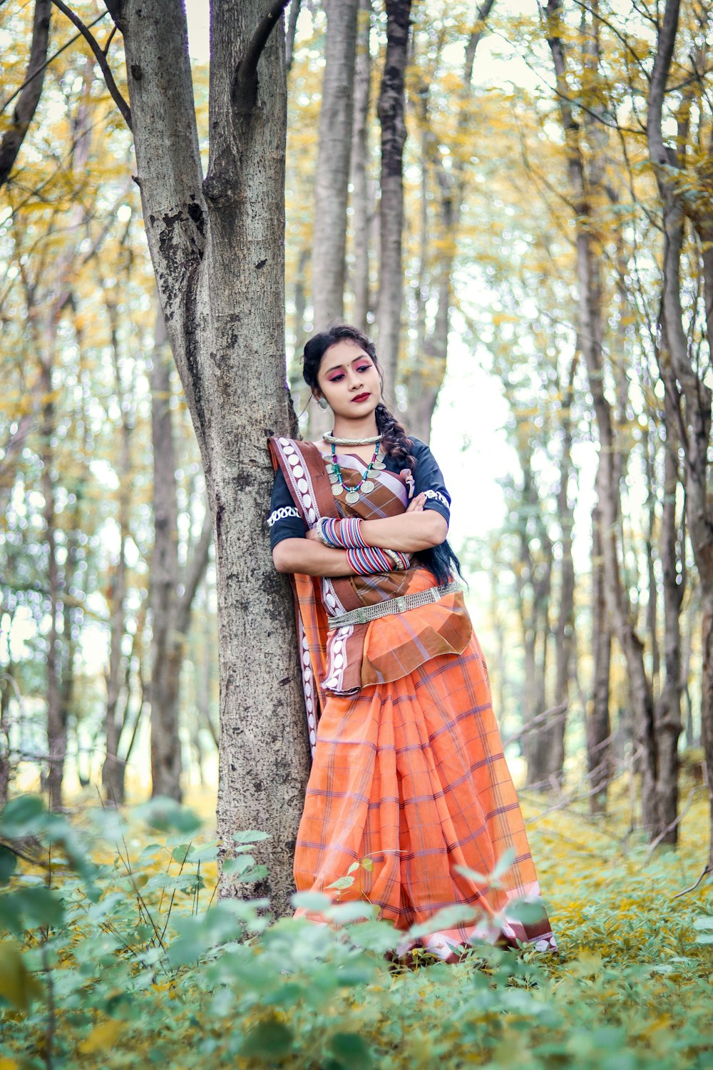 Una donna appoggiata a un albero in una foresta