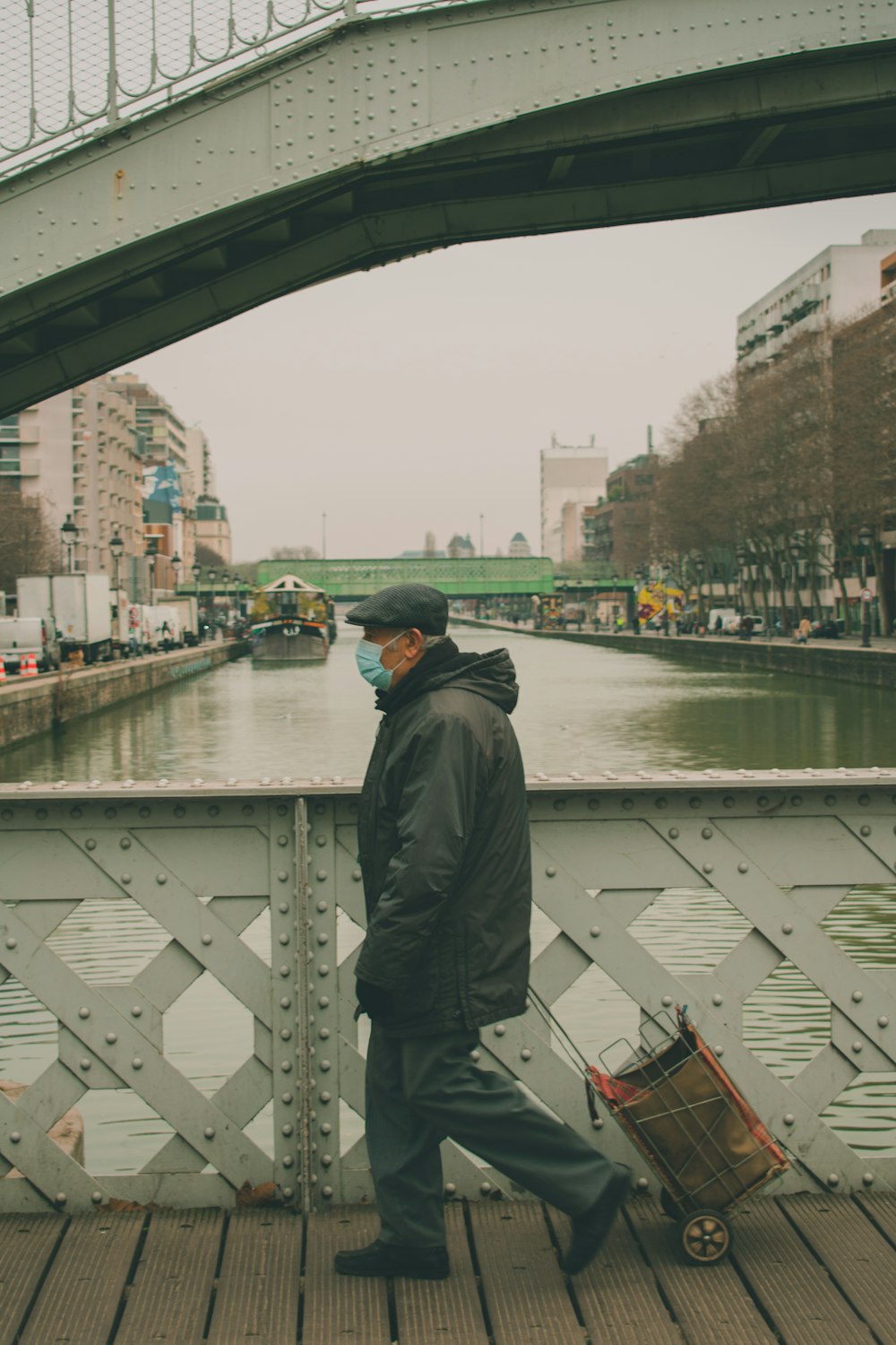 a man walking across a bridge while wearing a face mask