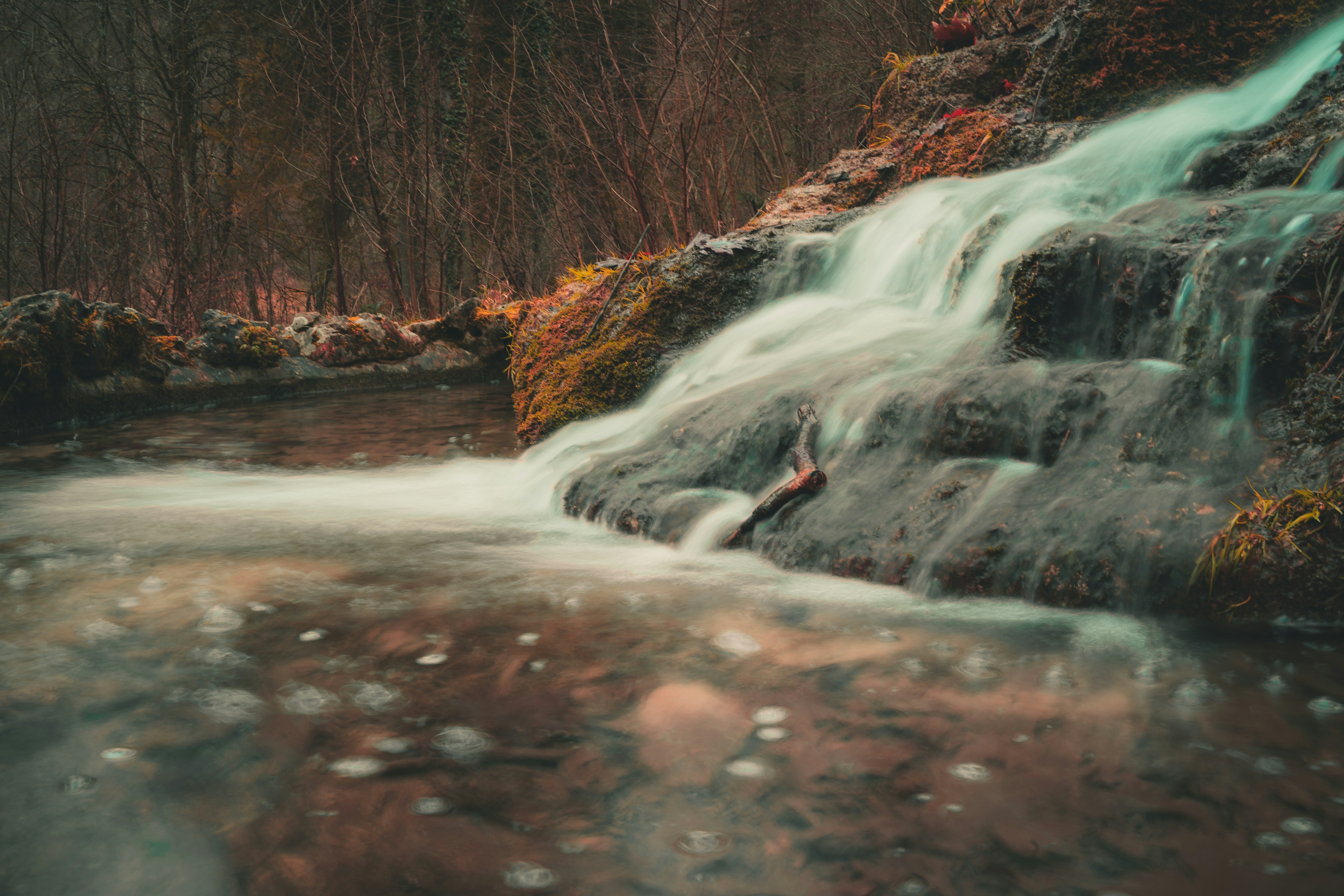 a small waterfall in the middle of a forest, 