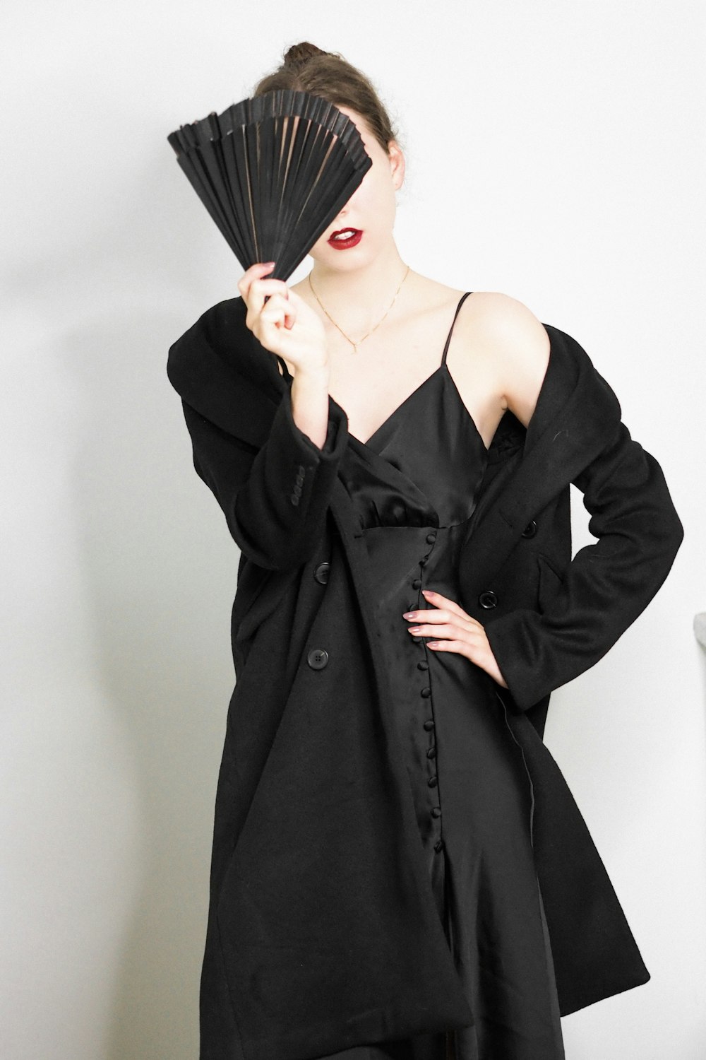a woman in a black dress holding a fan