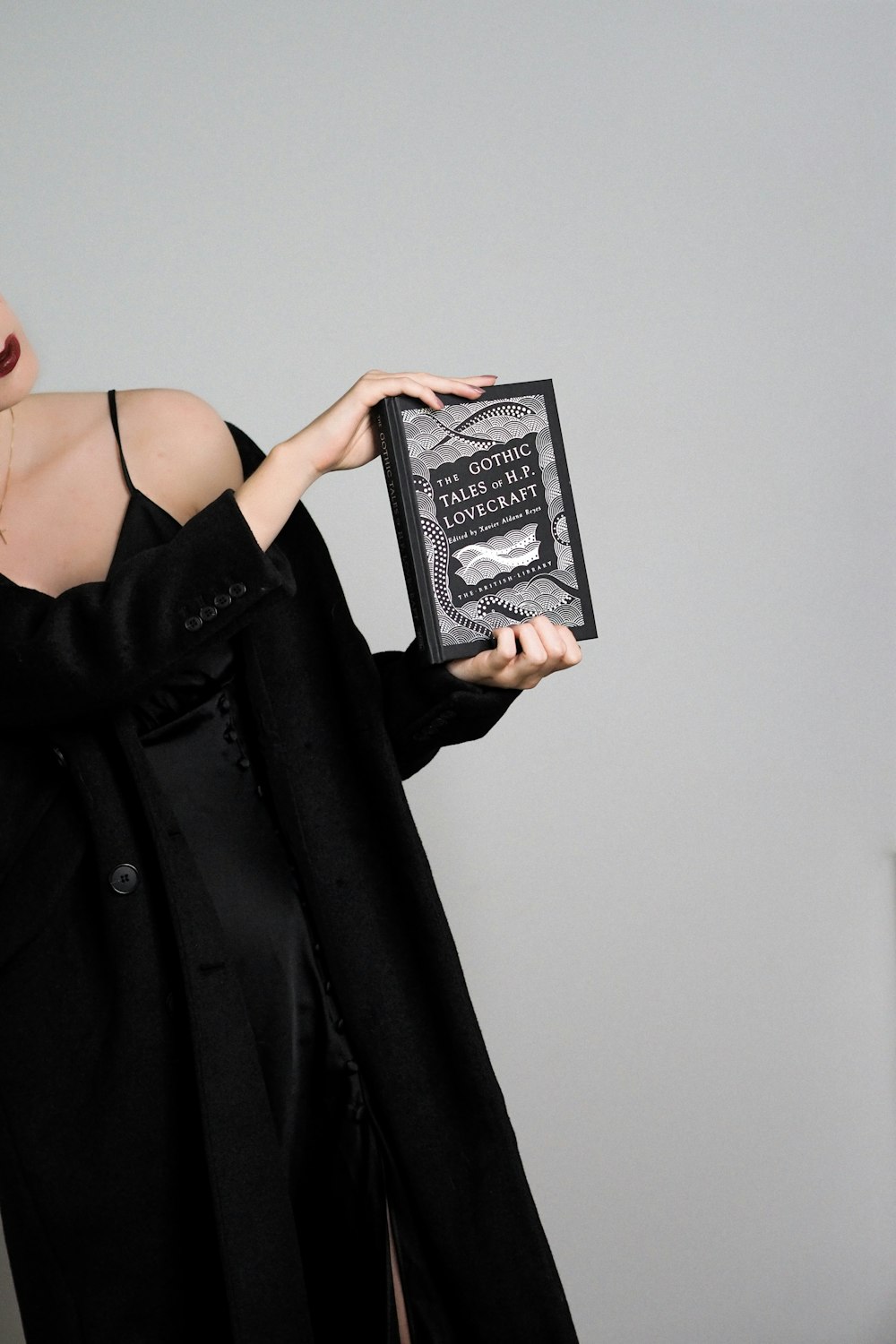 a woman in a black dress holding a book