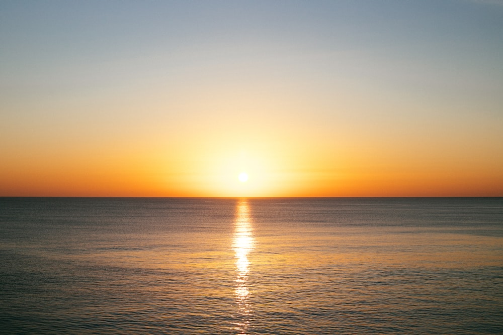 a large body of water with a sunset in the background