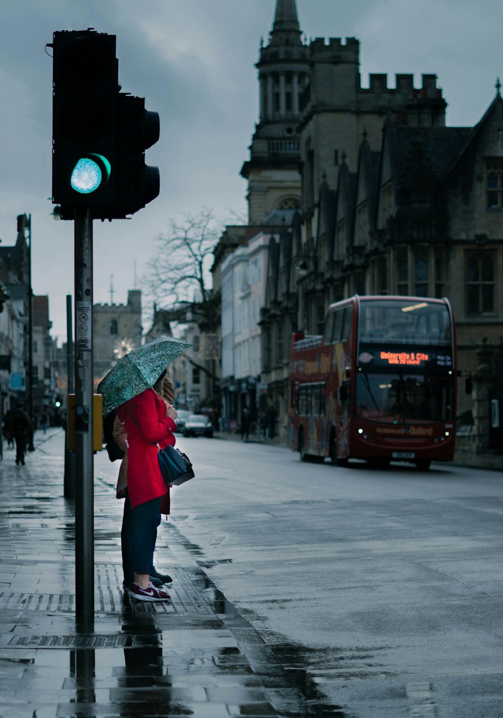 Una mujer parada bajo un paraguas junto a un semáforo