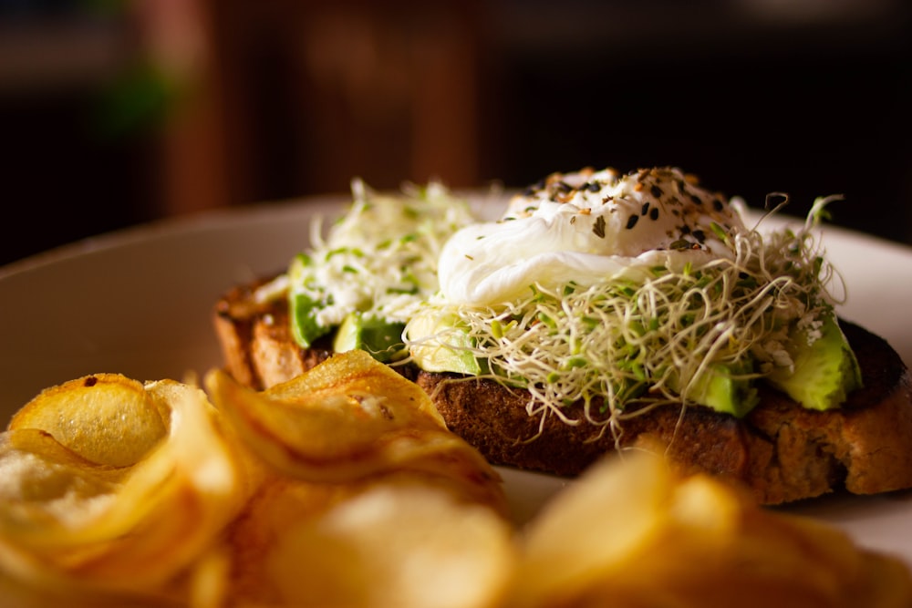 a white plate topped with a sandwich and potato chips