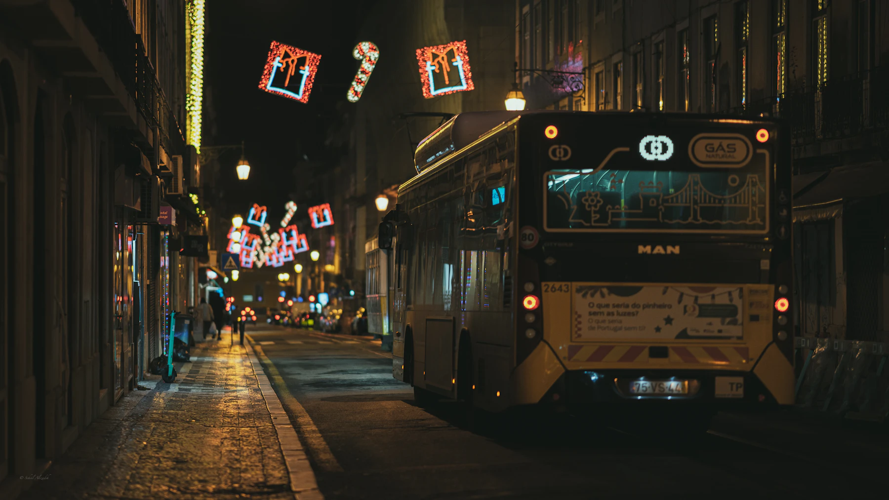 A bus on a decorated city street at night