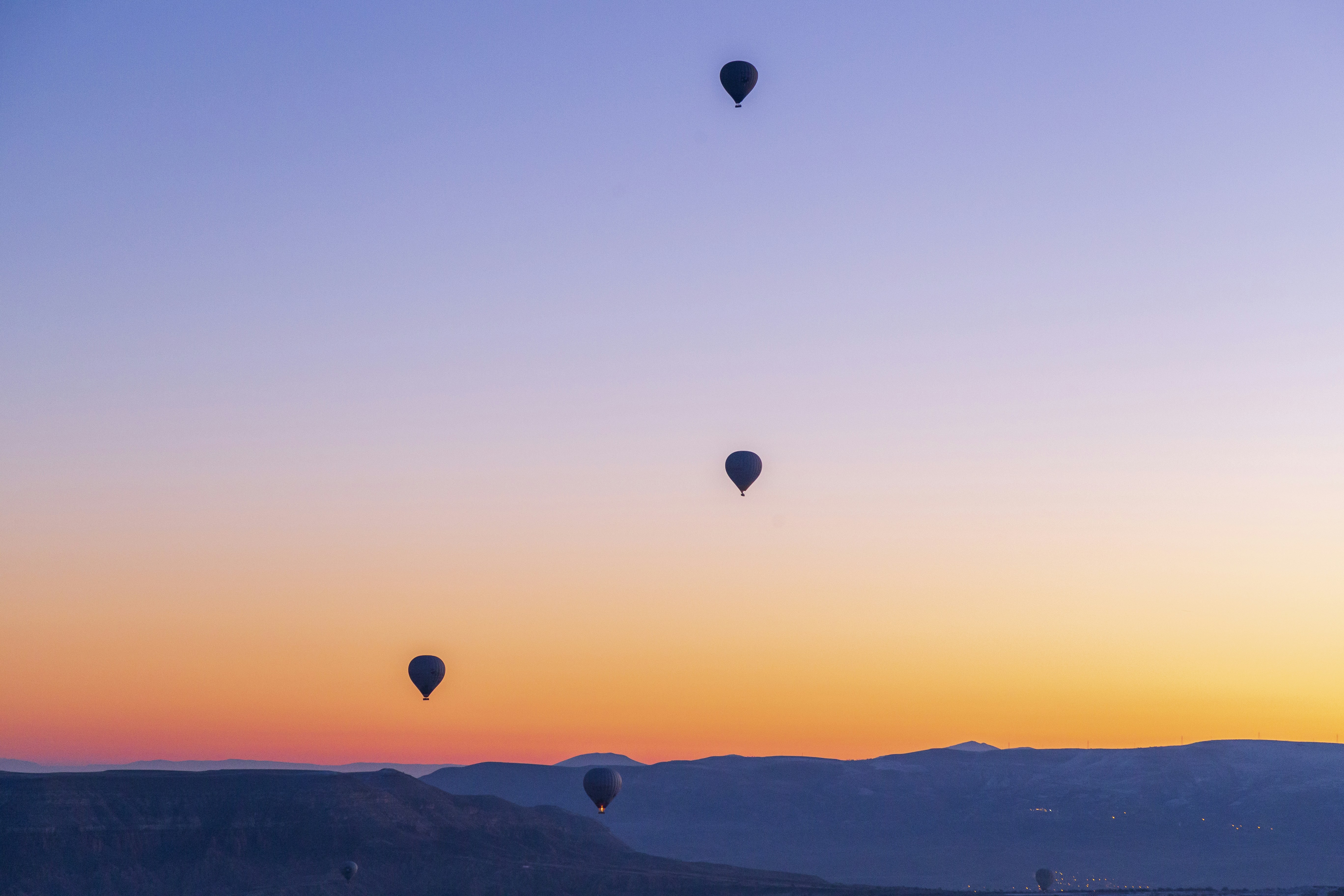 a group of hot air balloons flying in the sky, Hot air balloons flying over spectacular Cappadocia. Beautiful view of hot air balloons floating in sunrise blue sky over the mountain landscape of fairy chimneys