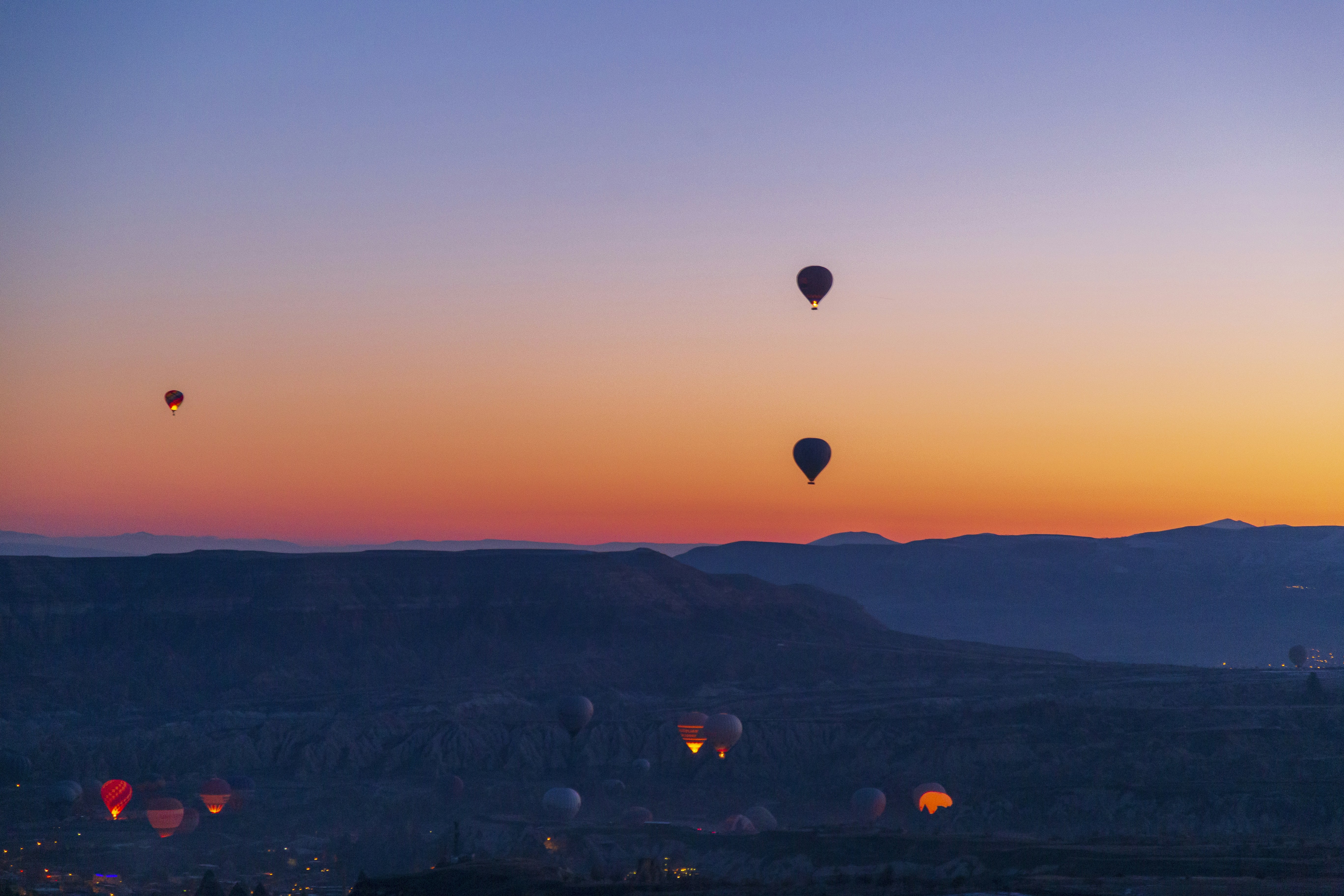 several hot air balloons flying in the sky, Hot air balloons flying over spectacular Cappadocia. Beautiful view of hot air balloons floating in sunrise blue sky over the mountain landscape of fairy chimneys
