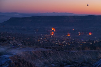 hot air balloons flying over a city at dusk