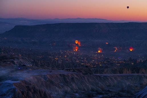 hot air balloons flying over a city at dusk