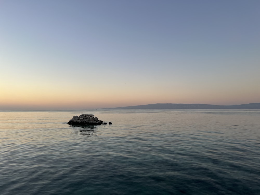 a large body of water with a small rock in the middle of it