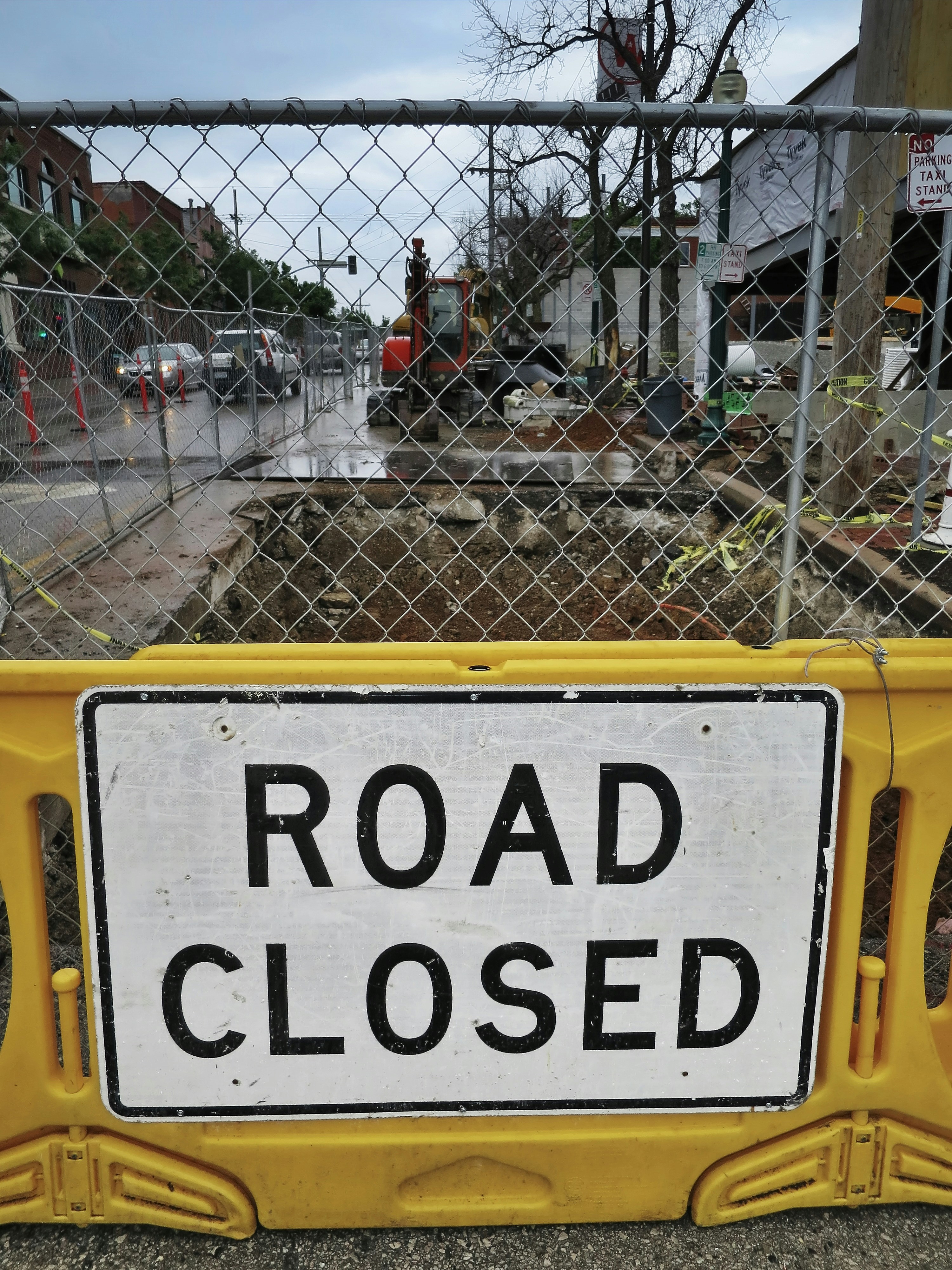 A road closed sign behind a chain link fence photo – Free Sign Image on ...