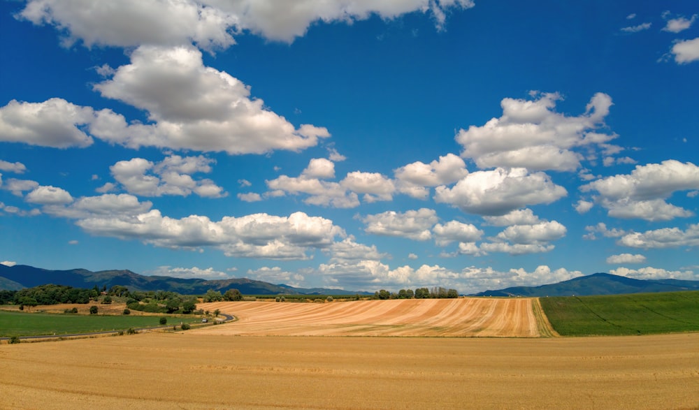 a large field with a sky filled with clouds