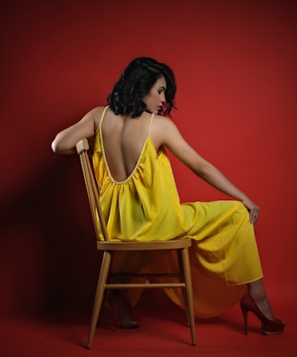 a woman in a yellow dress sitting on a chair