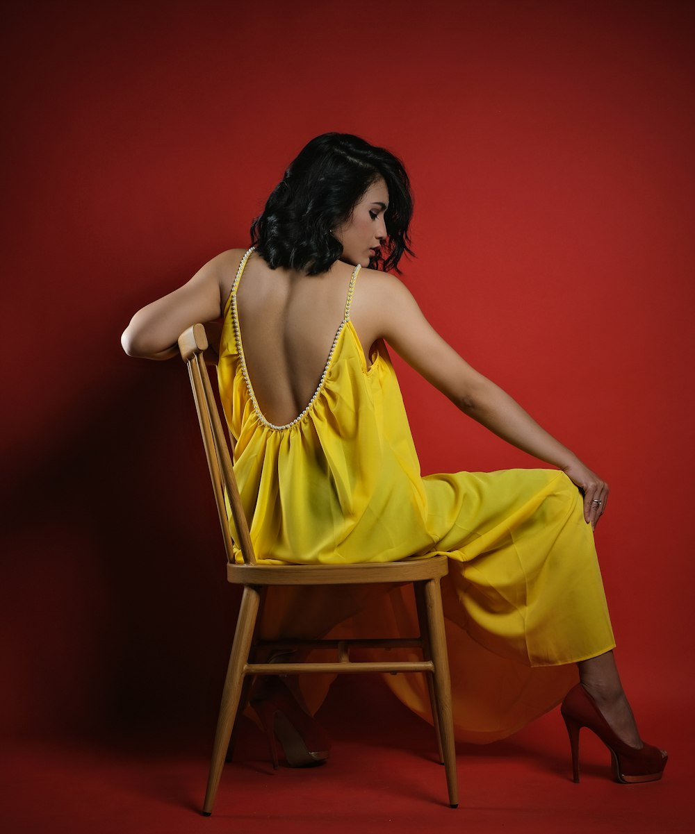 a woman in a yellow dress sitting on a chair