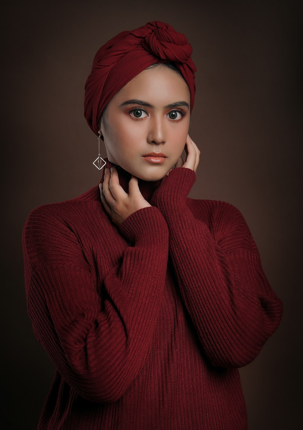 a woman wearing a red sweater and a turban
